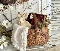 a stuffed rabbit sitting in a basket next to flowers