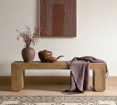 a wooden bench sitting in front of a painting and vases on top of it