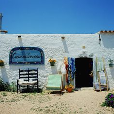 a white building with a sign and chairs outside