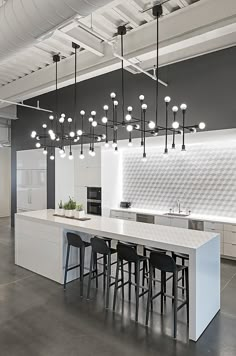 an open kitchen and dining area with white counter tops, black chairs and bar stools