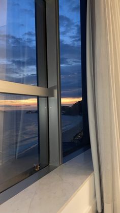 a window with curtains and the ocean outside