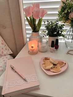 a table topped with a plate of pancakes next to a candle and vase filled with flowers