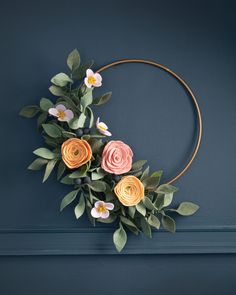 a wreath with flowers and leaves hanging on the wall