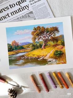 some crayons are laying on the table next to an artist's painting