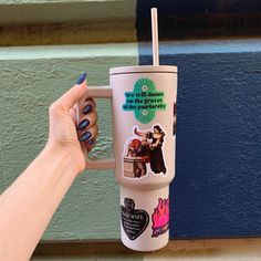 a woman's hand holding a cup with stickers on it