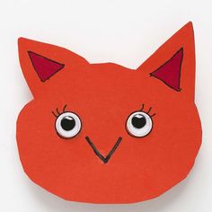 an orange paper cut out with eyes on it's face and the shape of a cat