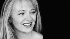 a black and white photo of a woman with long blonde hair smiling at the camera