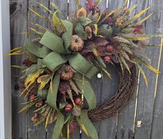 a wreath with leaves and acorns hanging on a fence