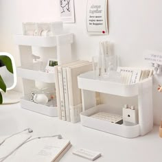 a white desk topped with lots of books and other office supplies on top of it