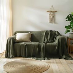 a living room with a couch covered in a green blanket and two pillows on the floor