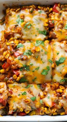 an enchilada casserole with meat and vegetables in a white dish