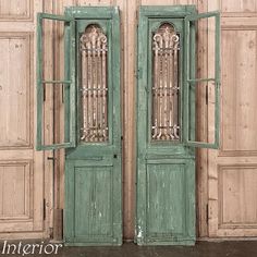 an old pair of green double doors with glass inserts