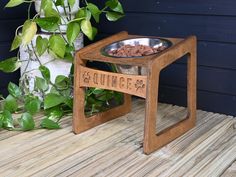 a wooden table with a dog bowl on it next to some plants and a potted plant