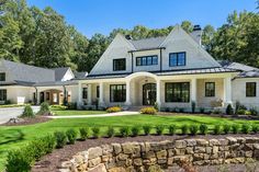 a large white house with lots of windows and grass in front of the house is surrounded by trees