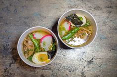 two bowls filled with food sitting on top of a stone counter next to each other