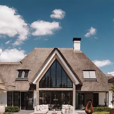 a large house with a thatched roof and lawn furniture in front of the entrance