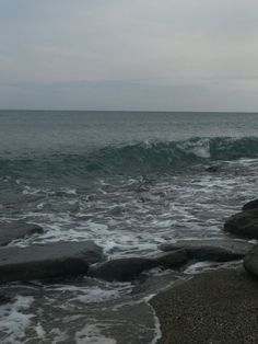 an ocean view with waves crashing on the rocks