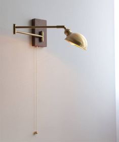 a wall mounted light on the side of a white wall next to a lamp shade