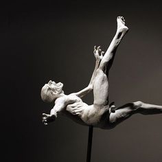 a sculpture of a man on a pole with his legs spread out in the air