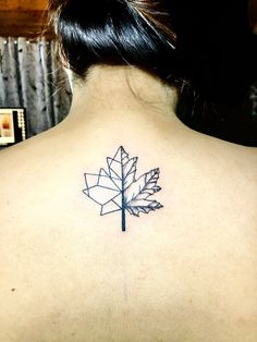 the back of a woman's neck with a leaf tattoo on it