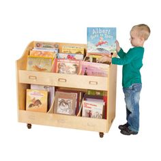 a little boy standing next to a wooden book stand