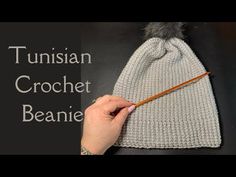 someone is knitting a beanie with a pencil in their hand and the text reads, tunishan crochet beanie