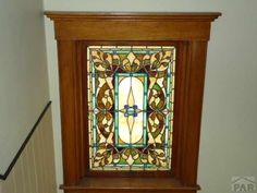 a stained glass window on the side of a stair case above a bannister