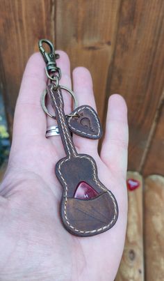 a hand holding a key chain with a heart shaped instrument on it's side