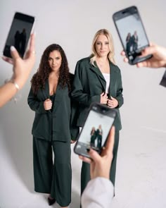 two women are taking pictures with their cell phones while another woman is holding up her phone