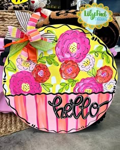 a basket with flowers on it sitting in front of a sign that says hello kitty