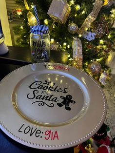 a white plate with the words cookies for santa written on it and a christmas tree in the background