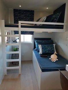 a bunk bed with blue sheets and pillows in a room that looks like it has been built into the wall