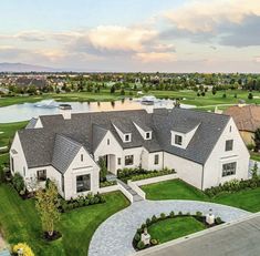 an aerial view of a large home with lots of grass and water in the background