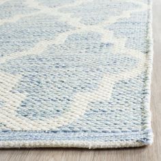 a blue and white rug on top of a wooden floor with a light colored area rug