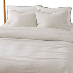 a bed with white linens and pillows on it