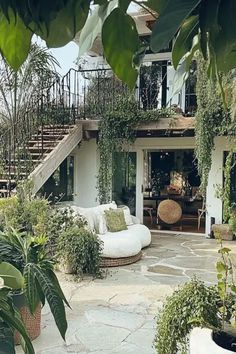 an outdoor living area with white furniture and greenery on the stairs to the second floor