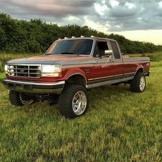 a red pick up truck parked on top of a lush green field