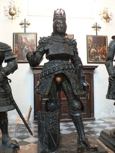 two statues of knights standing next to each other in a room with paintings on the wall