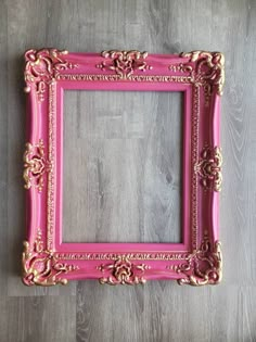 a pink and gold frame sitting on top of a wooden floor