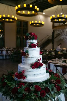 a white wedding cake with red flowers and pine cones