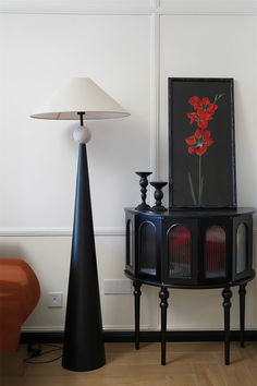 a black table with a lamp next to it on top of a hard wood floor