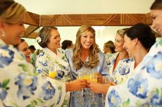 a group of women standing next to each other in robes and holding wine glasses together