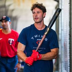 a man holding a baseball bat while standing next to another man in red and blue shirts