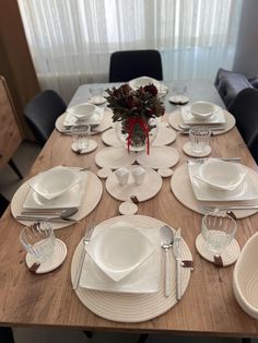 the table is set with white dishes and place settings