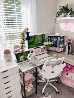 a white desk topped with a computer monitor next to a pink heart shaped bed pillow