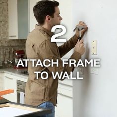 a man is working on a wall with the words 2 attach frame to wall