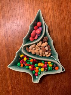 a ceramic christmas tree with candy and candies in it on a wooden table top