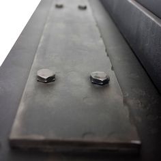 two metal knobs are on the side of a steel structure with rivets