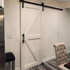 a white barn door in a kitchen next to a refrigerator and table with two chairs