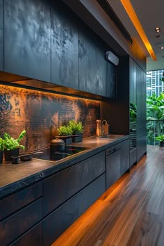 a kitchen with wooden flooring and black cabinetry next to a plant filled wall